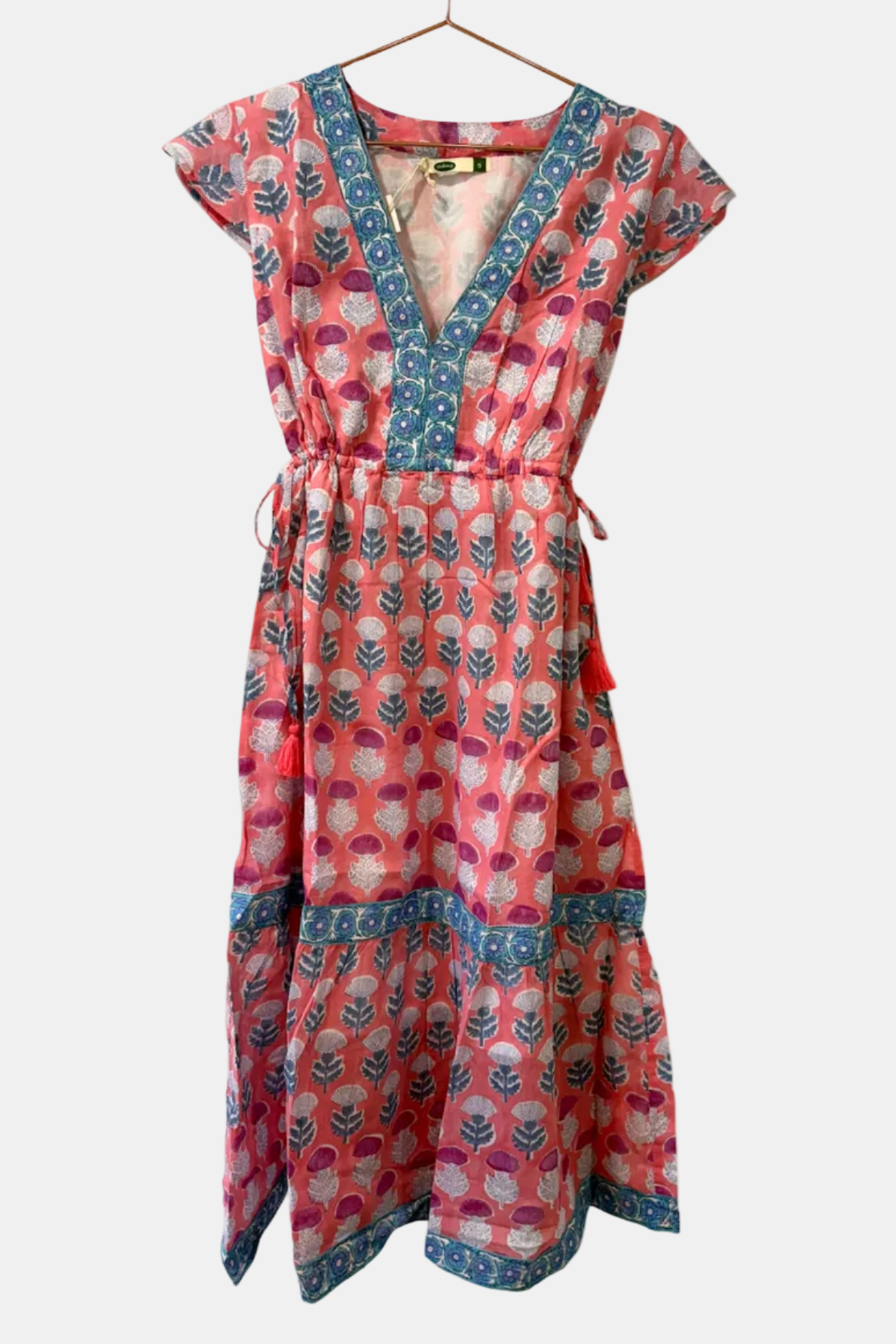 Red and blue patterned dress on a hanger against a white background