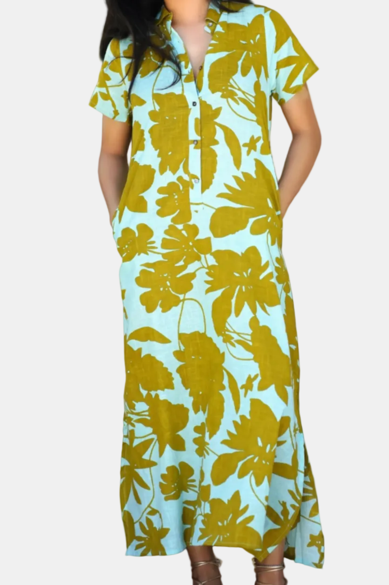 A woman wearing a short-sleeve midi dress with a bold yellow floral print on a light mint green background, standing in front of a dark brown wooden door.