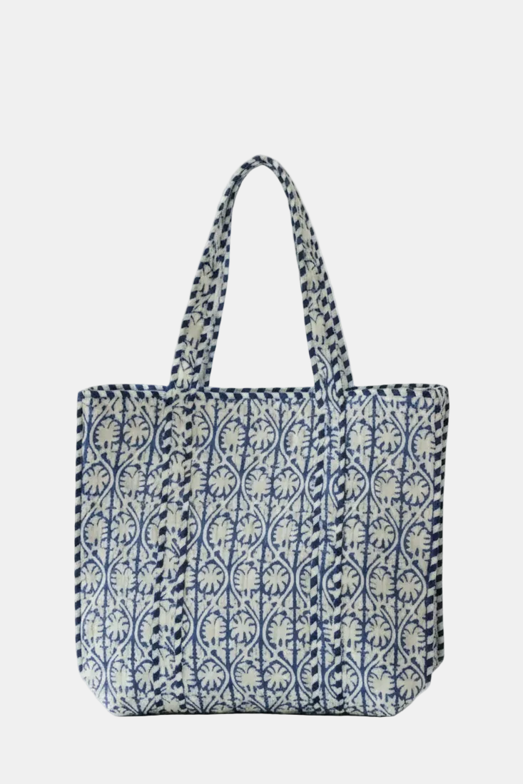 A canvas tote bag with a blue and white floral block print pattern and matching shoulder straps, shown against a plain white background.