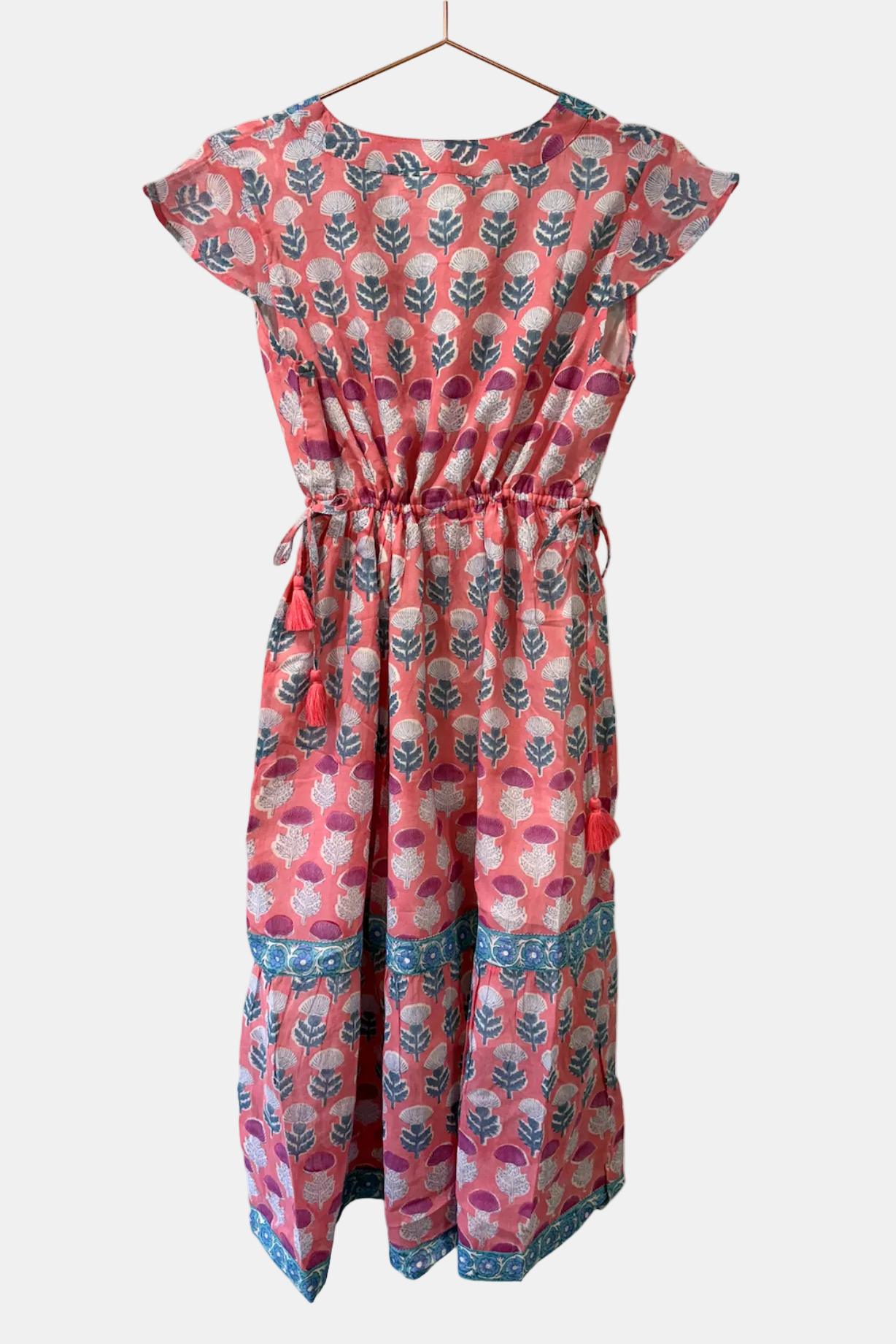 Pink patterned dress on a hanger against a white background