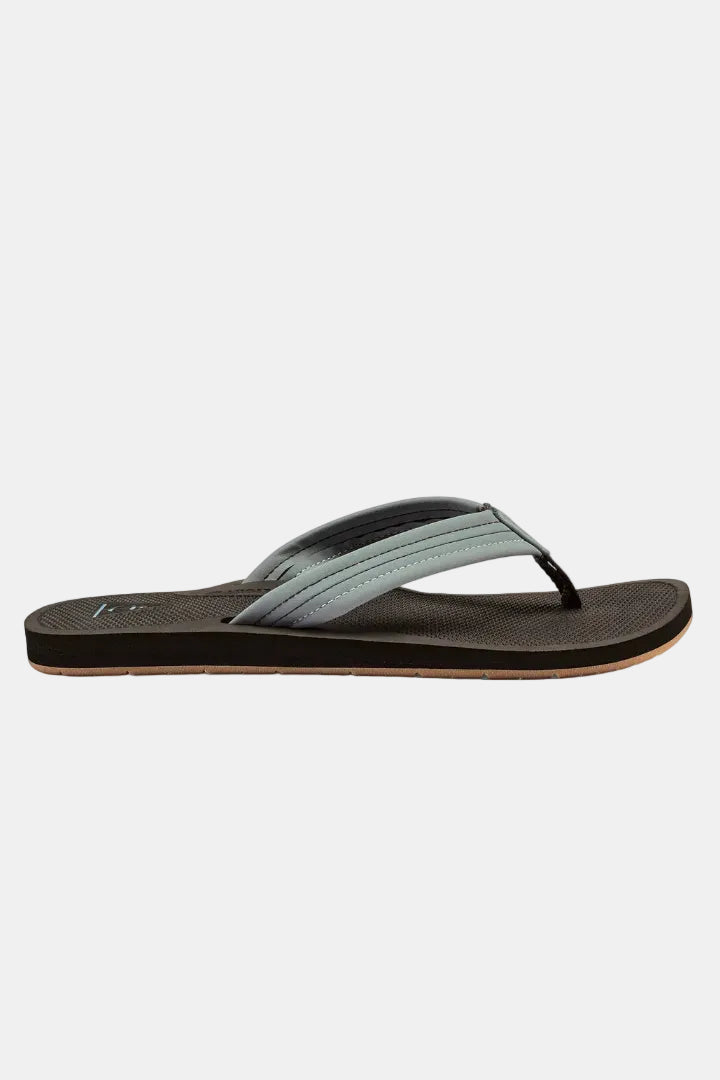 A single flip-flop sandal shown in profile against a plain white background. The sandal features a dark brown textured footbed and sole, a black toe post, and a wide strap in a muted sage green and gray gradient.
