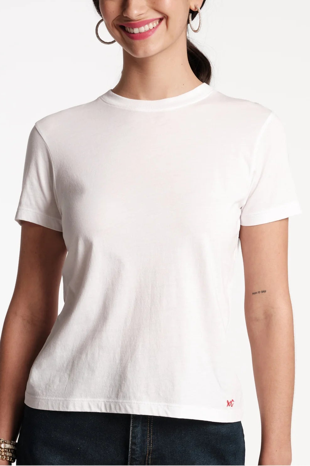 Woman wearing a plain white t-shirt with a small logo on a white background