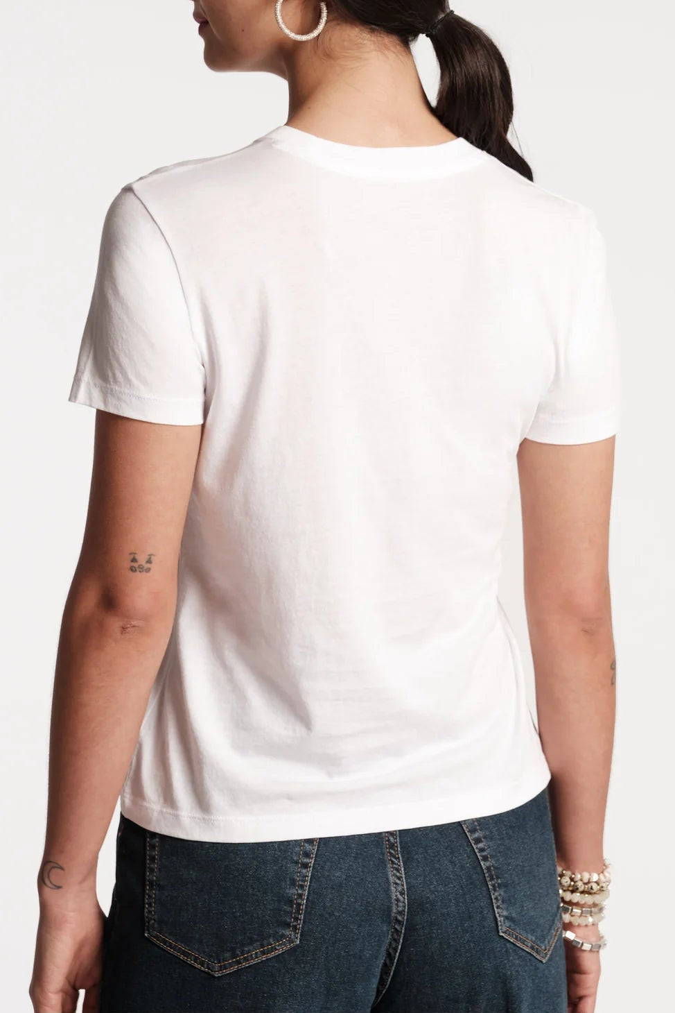 Person wearing a plain white t-shirt on a light gray background