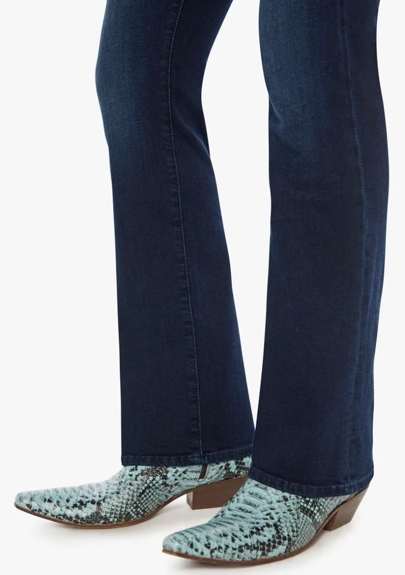 Close-up of a person's legs wearing dark blue flared jeans and pointed-toe snakeskin-pattern ankle boots in a light blue-green and black print, set against a plain white background.