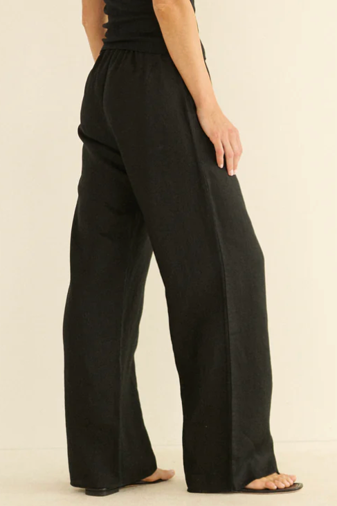 Woman wearing a black jumpsuit on a beige background