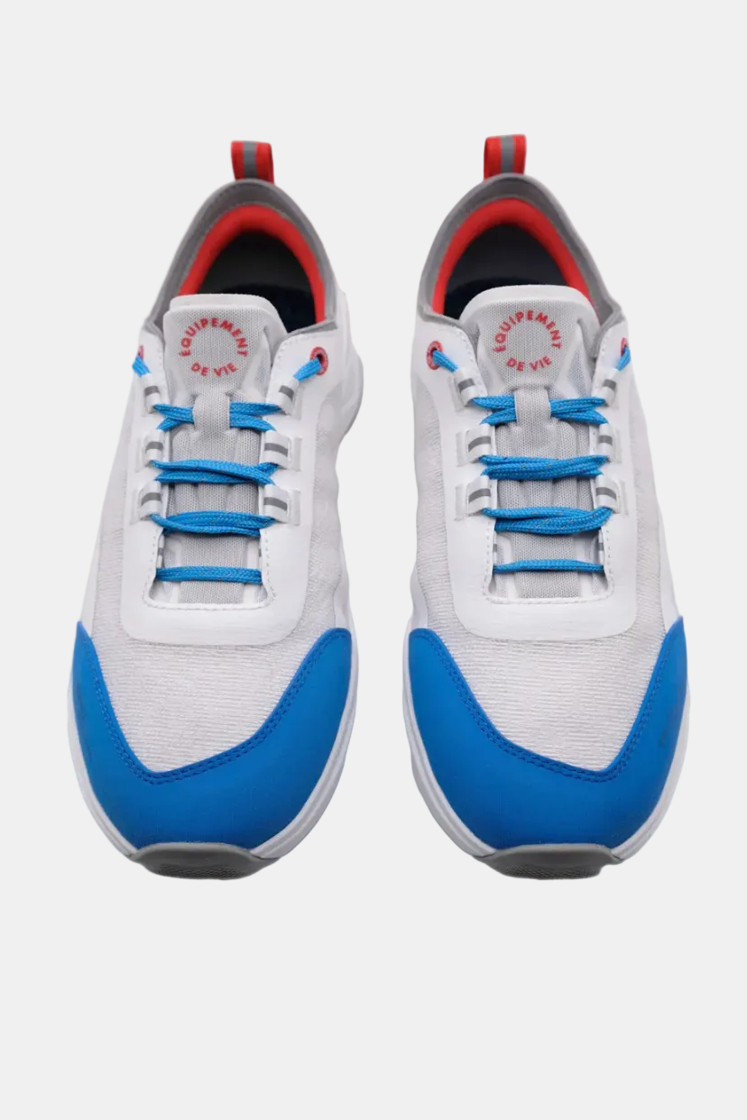 White sneakers with blue soles and laces on a white background