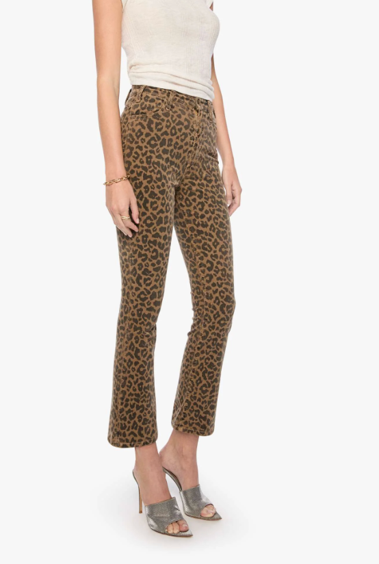 A model wearing brown and black leopard print cropped flare pants, paired with a cream top and gray heeled sandals, against a plain white background.
