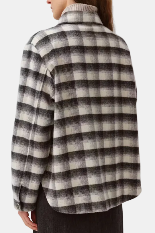 A model shown from the back wearing a long-sleeve plaid sweater with a high ribbed mock neck. The sweater features a checkered pattern in black, gray, and off-white.