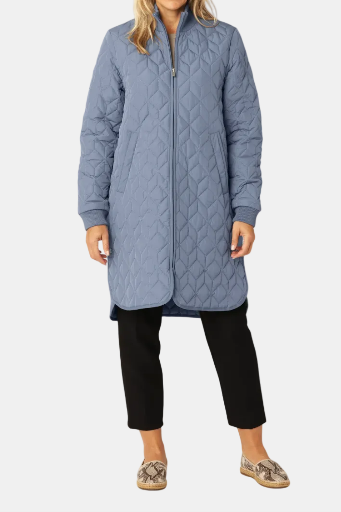 Woman wearing a long quilted blue jacket on a white background
