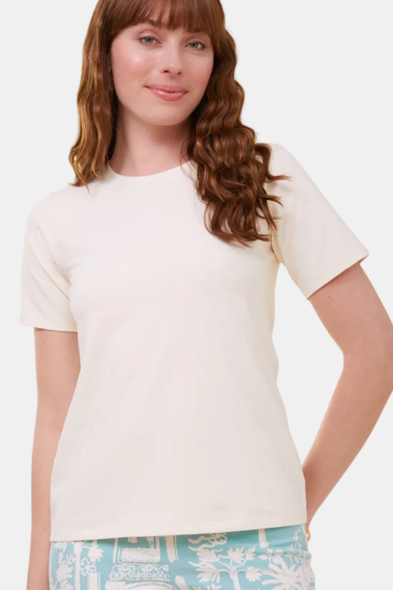 Woman wearing a plain white t-shirt with a light blue floral skirt on a white background