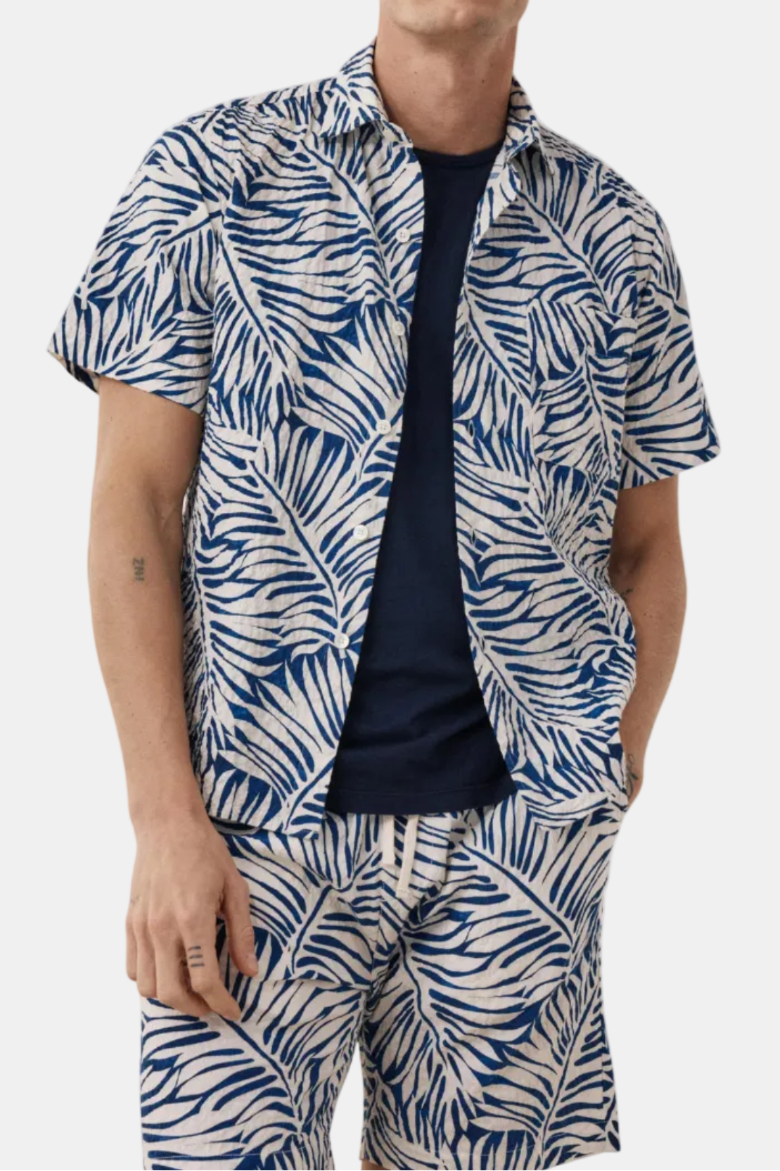 Man wearing a blue and white patterned shirt and pants on a white background