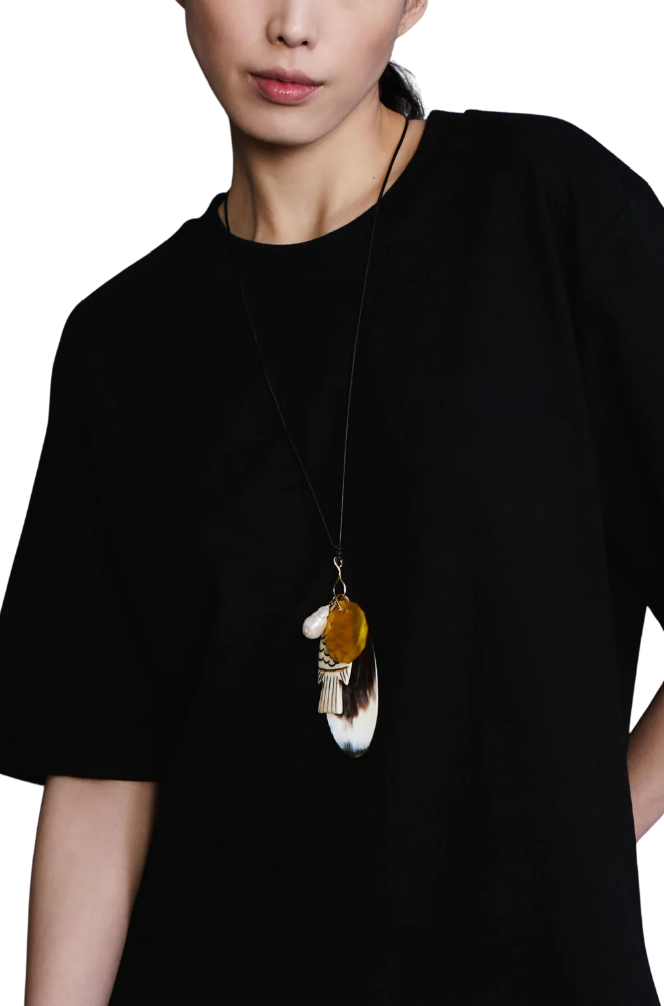 Person wearing a black shirt with a unique necklace featuring a large pendant.