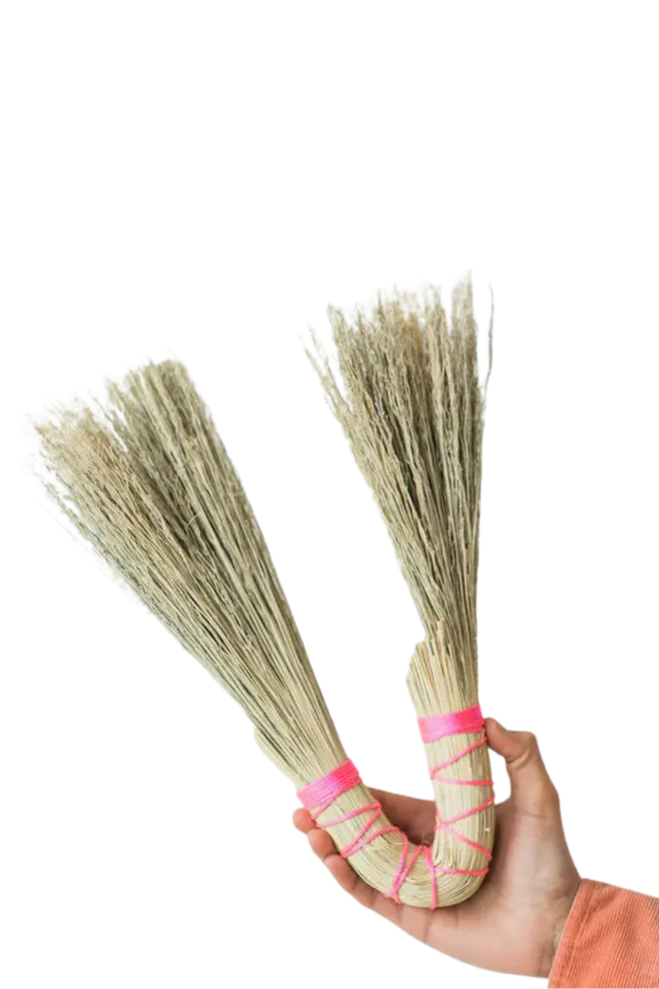Two brooms with pink handles held by a hand against a white background