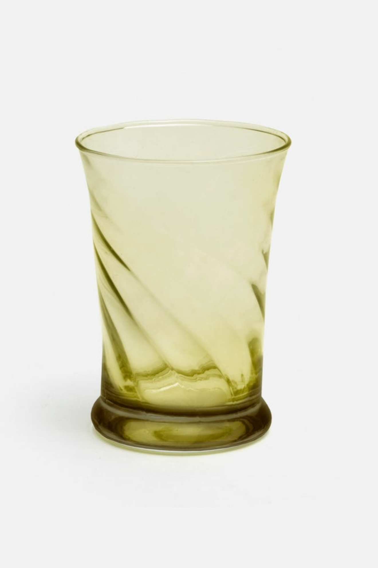 Green glass tumbler with twisted design on a white background