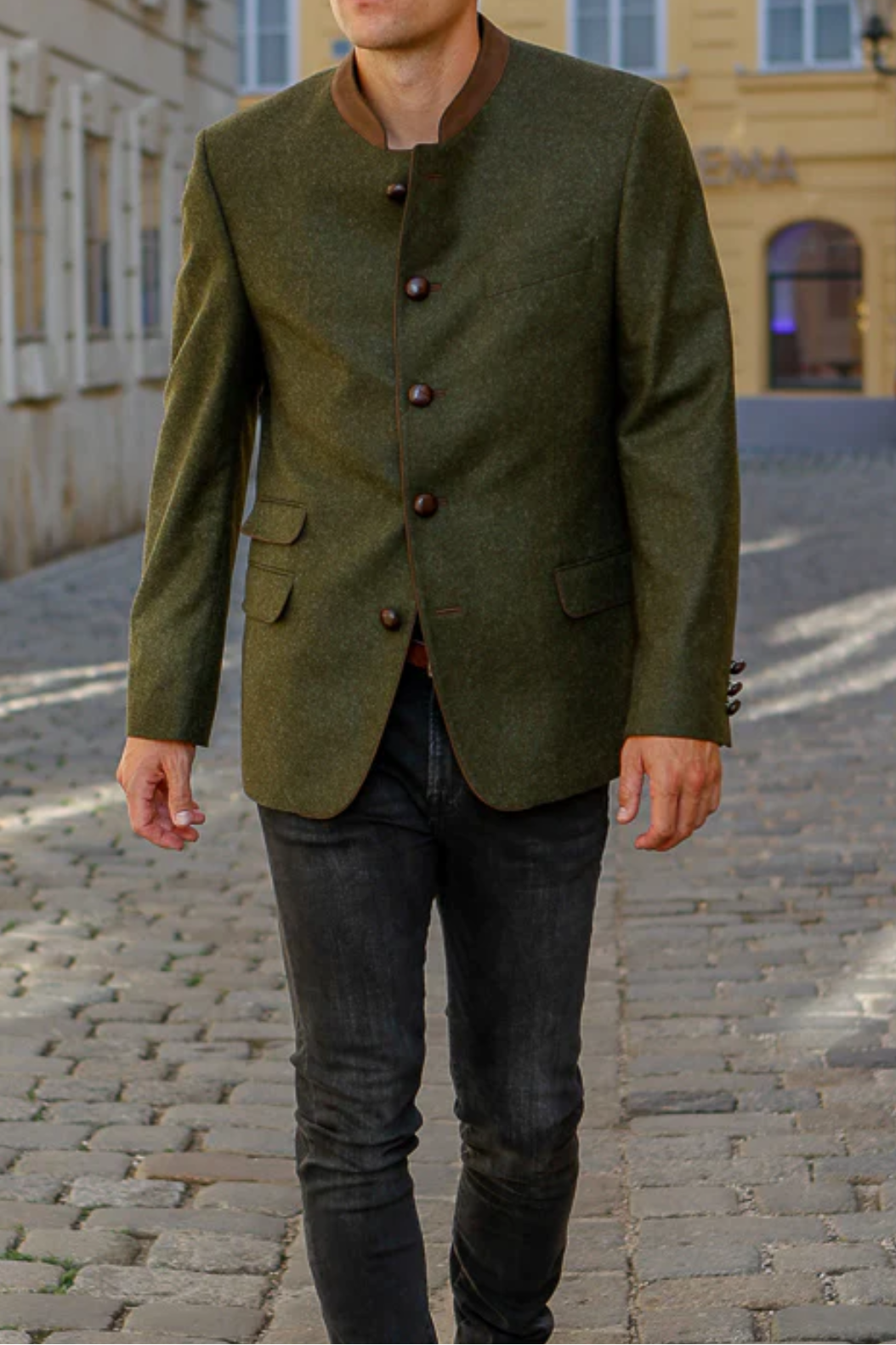 Man wearing a green jacket walking down a street with buildings in the background