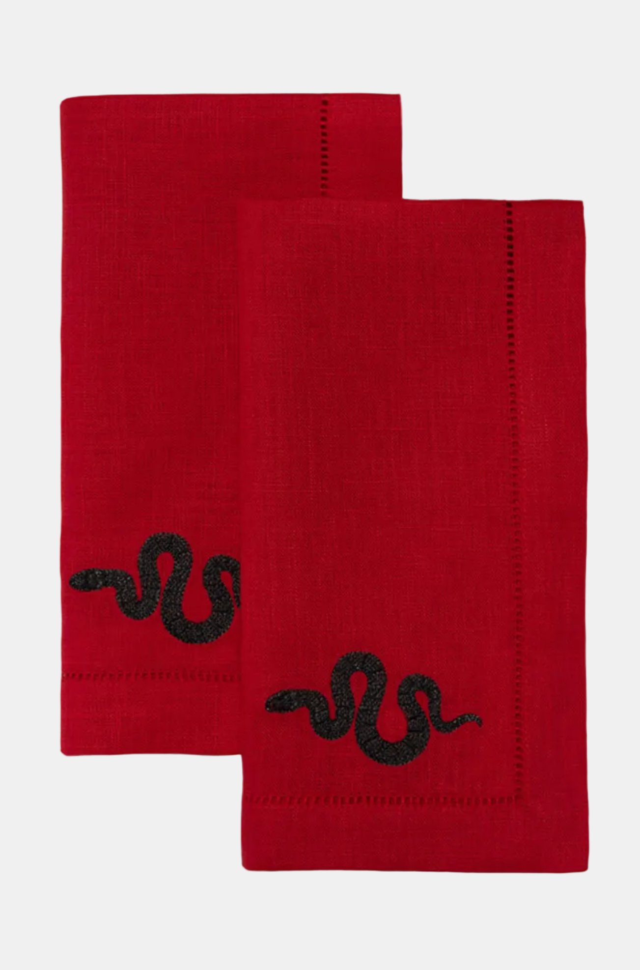 Two red napkins with black embroidered designs on a white background