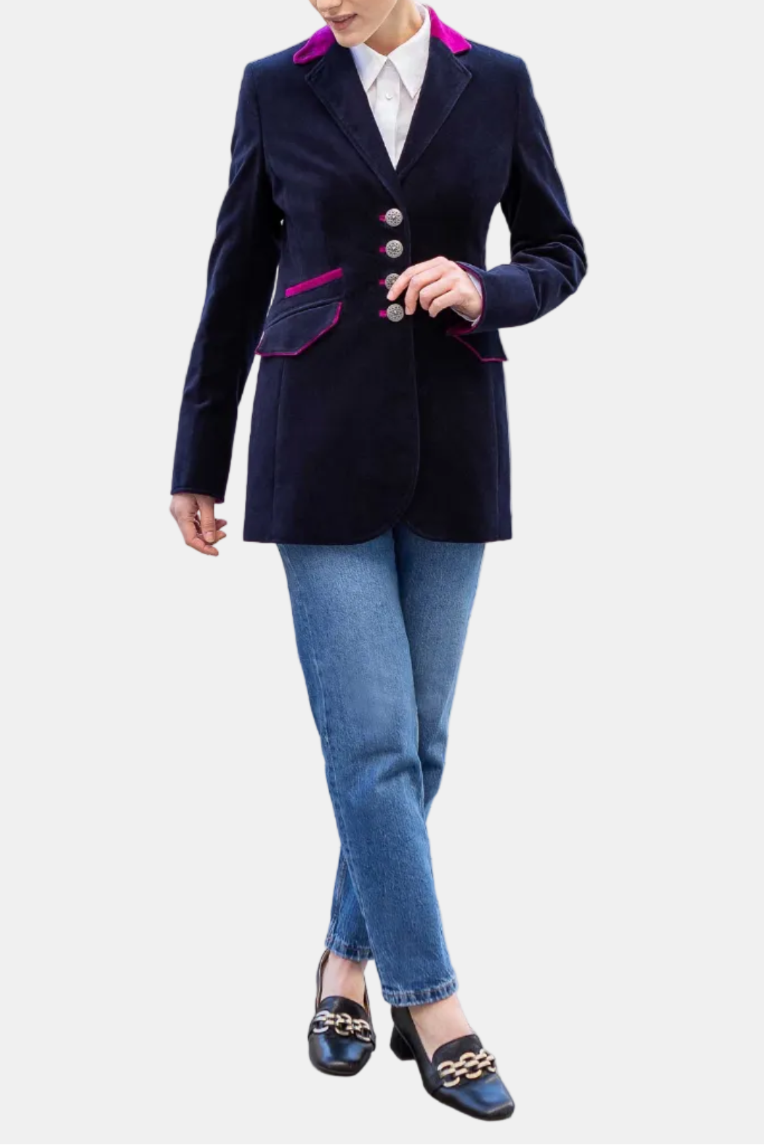 Woman wearing a navy blazer with pink accents and blue jeans on a city street.