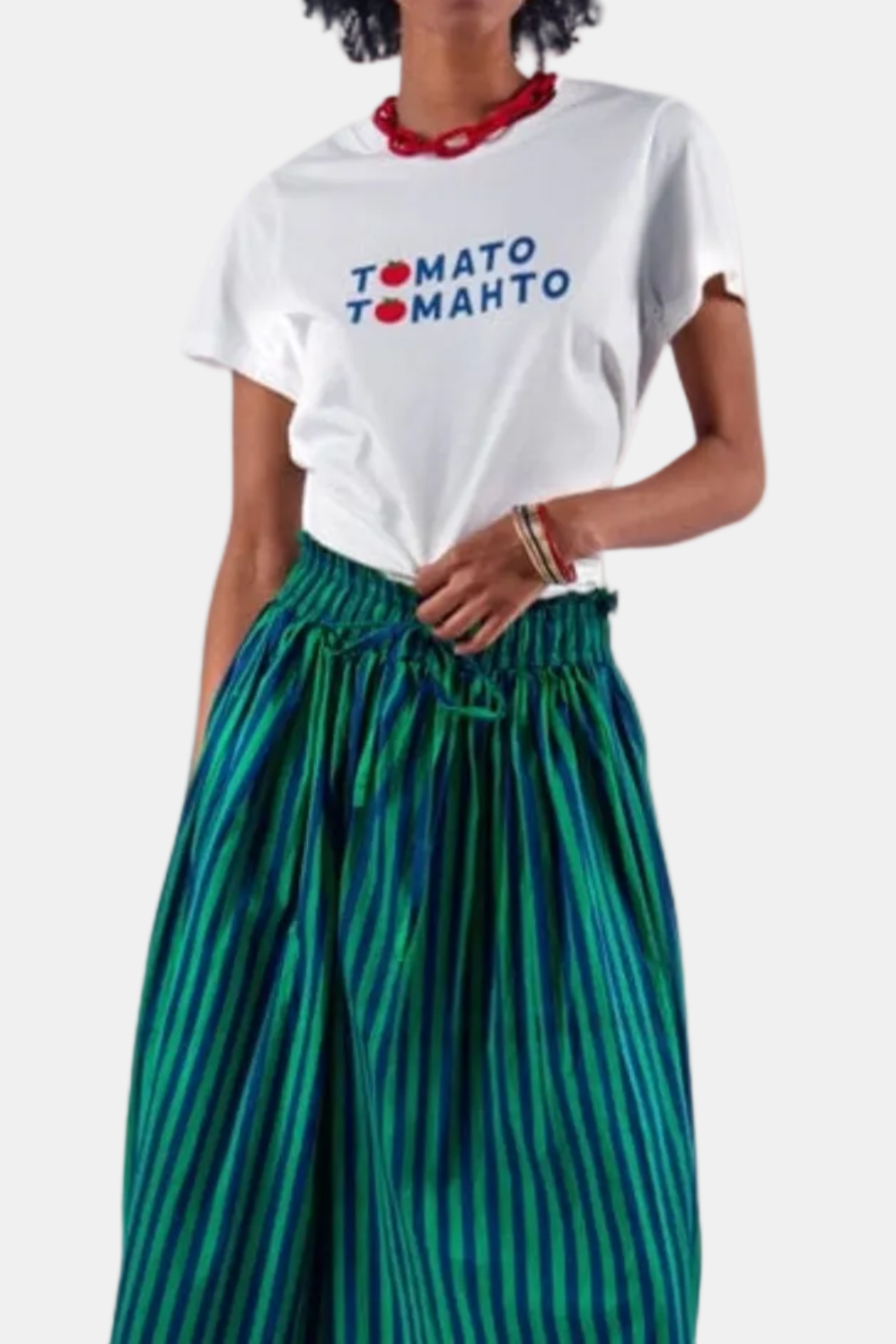 Woman wearing a white t-shirt with 'Tomato Tomato' text and green striped pants on a white background