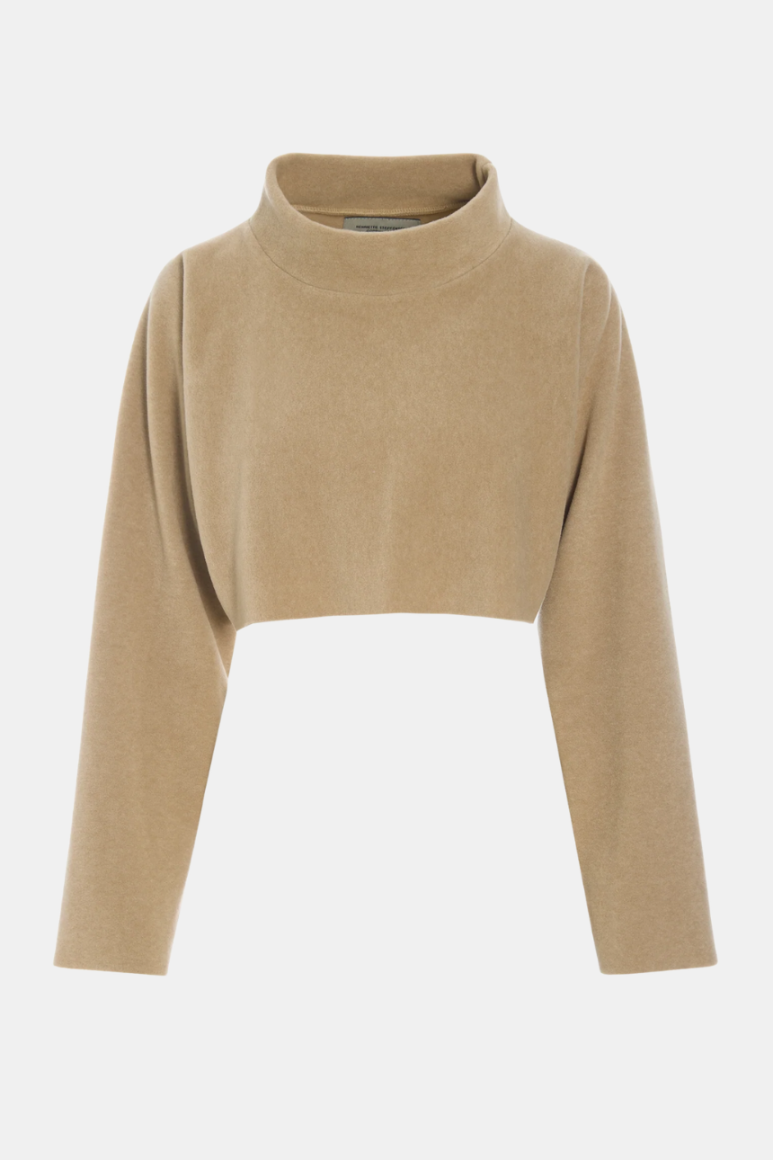 A cropped long-sleeve knit top in a warm camel beige color, featuring a mock neck and drop shoulders, shown against a plain light gray background.
