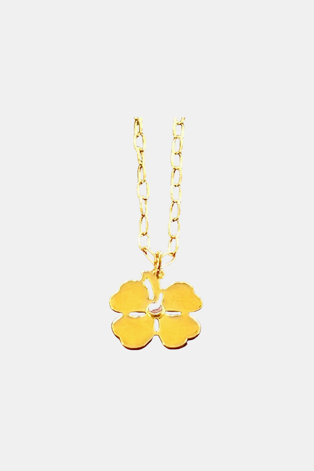 A gold-tone necklace featuring a four-leaf clover pendant with a small clear crystal accent in the center, suspended from a delicate link chain against a light gray background.