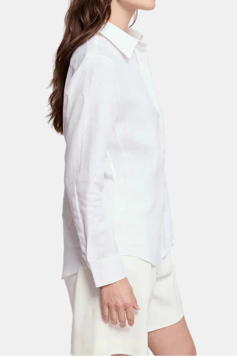 Woman wearing a white shirt and white pants against a plain background
