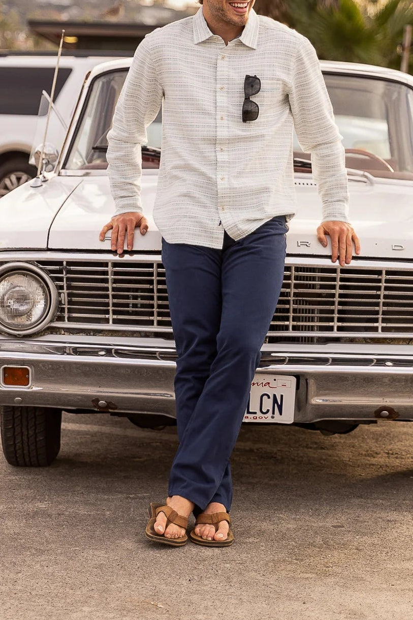 Man standing next to a vintage car with palm trees in the background