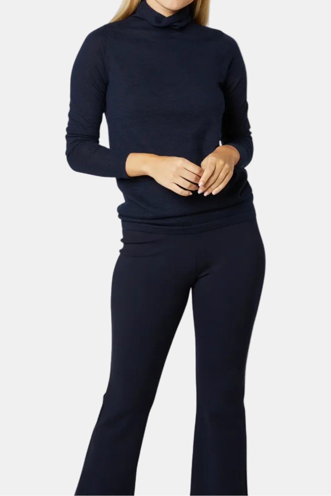 Woman wearing a navy blue turtleneck sweater and pants on a white background