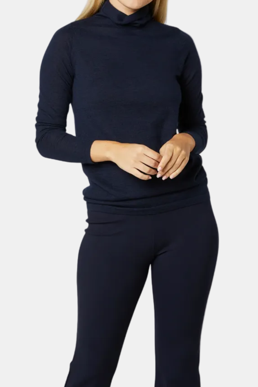 Woman wearing a navy blue turtleneck sweater and pants on a white background