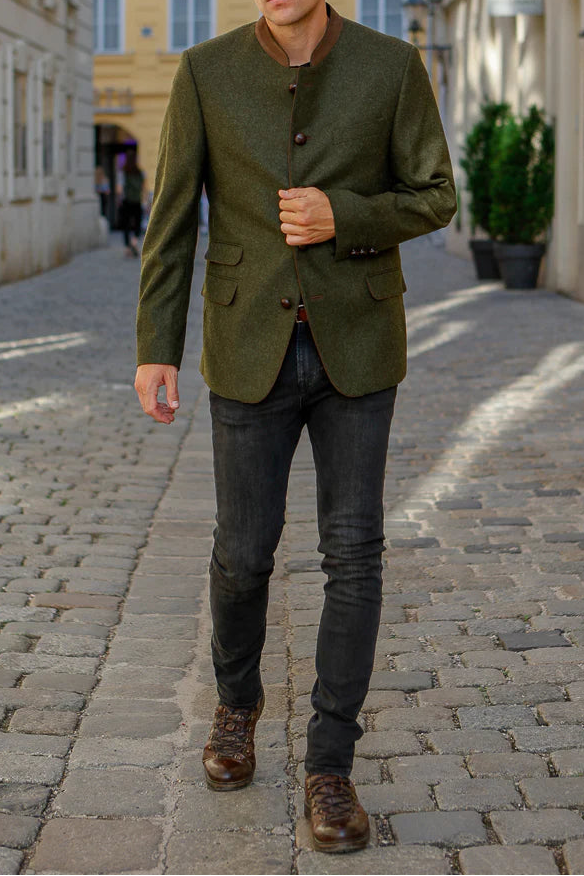 Man in a green jacket walking down a cobblestone street.
