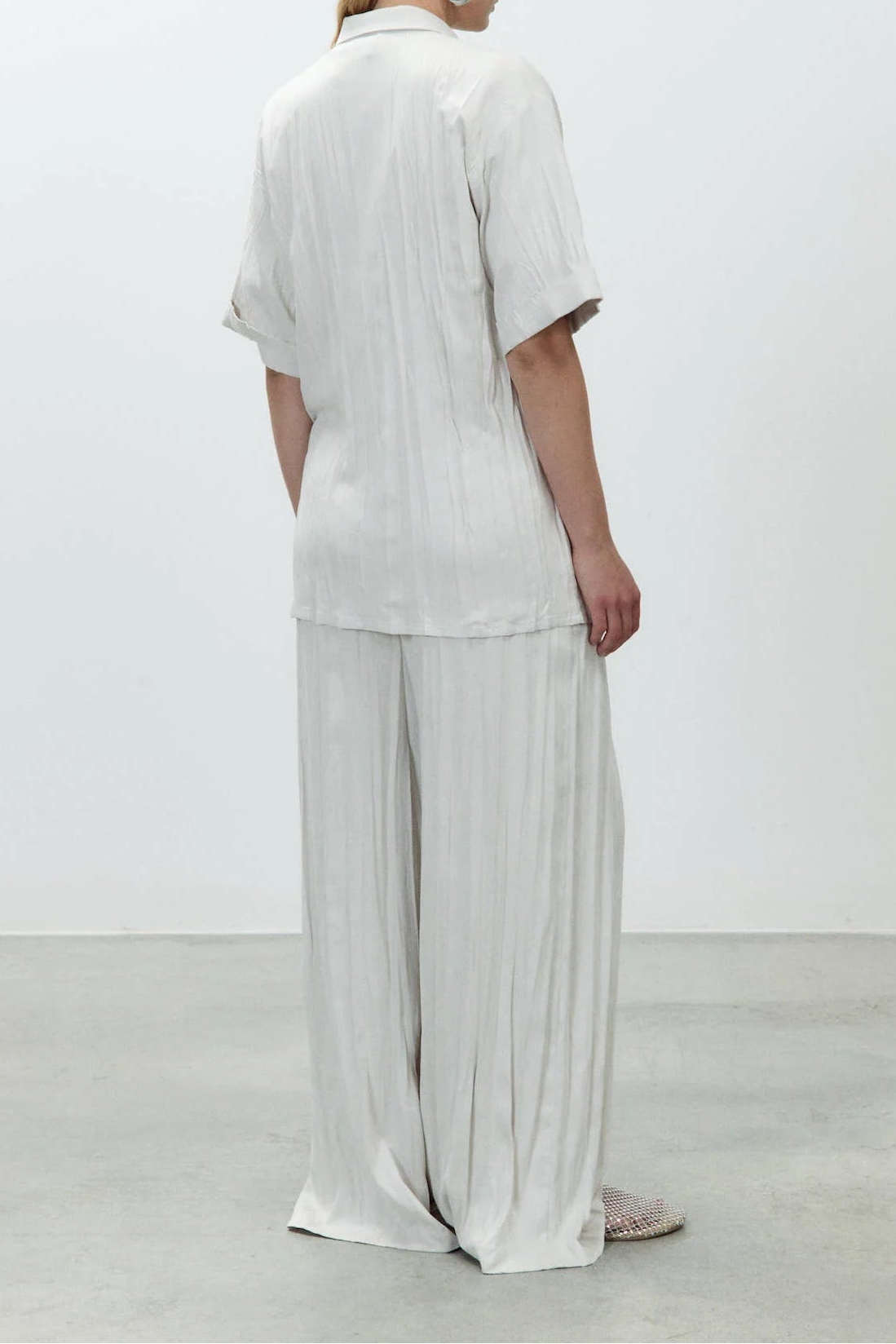 Person wearing a white outfit standing against a plain background