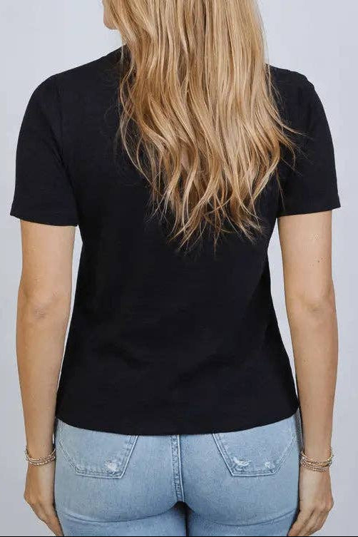 Person wearing a black t-shirt and light blue jeans against a plain background