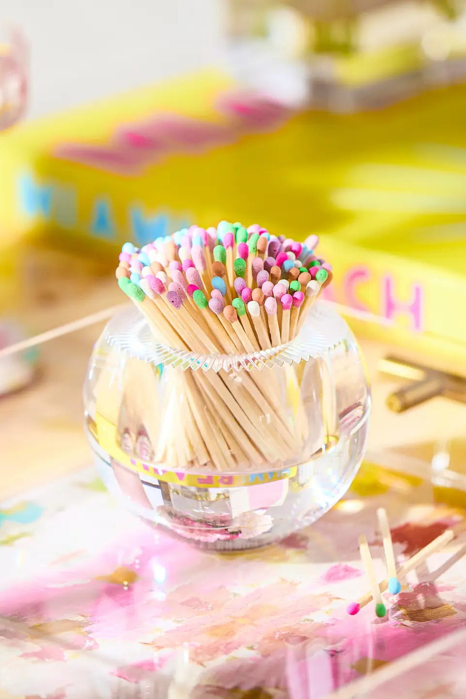 Clear container with colorful toothpicks on a decorative surface