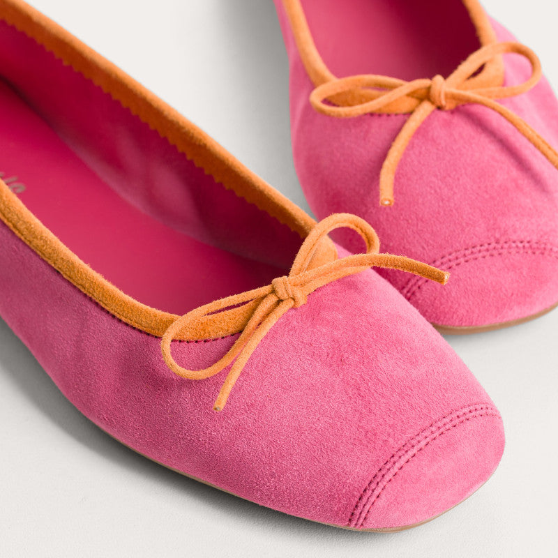 Pink flats with orange laces on a light gray background