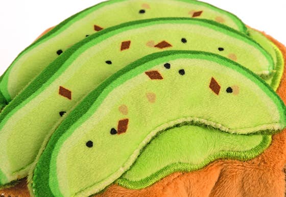 Avocado-shaped dog toy with brown seeds on a white background
