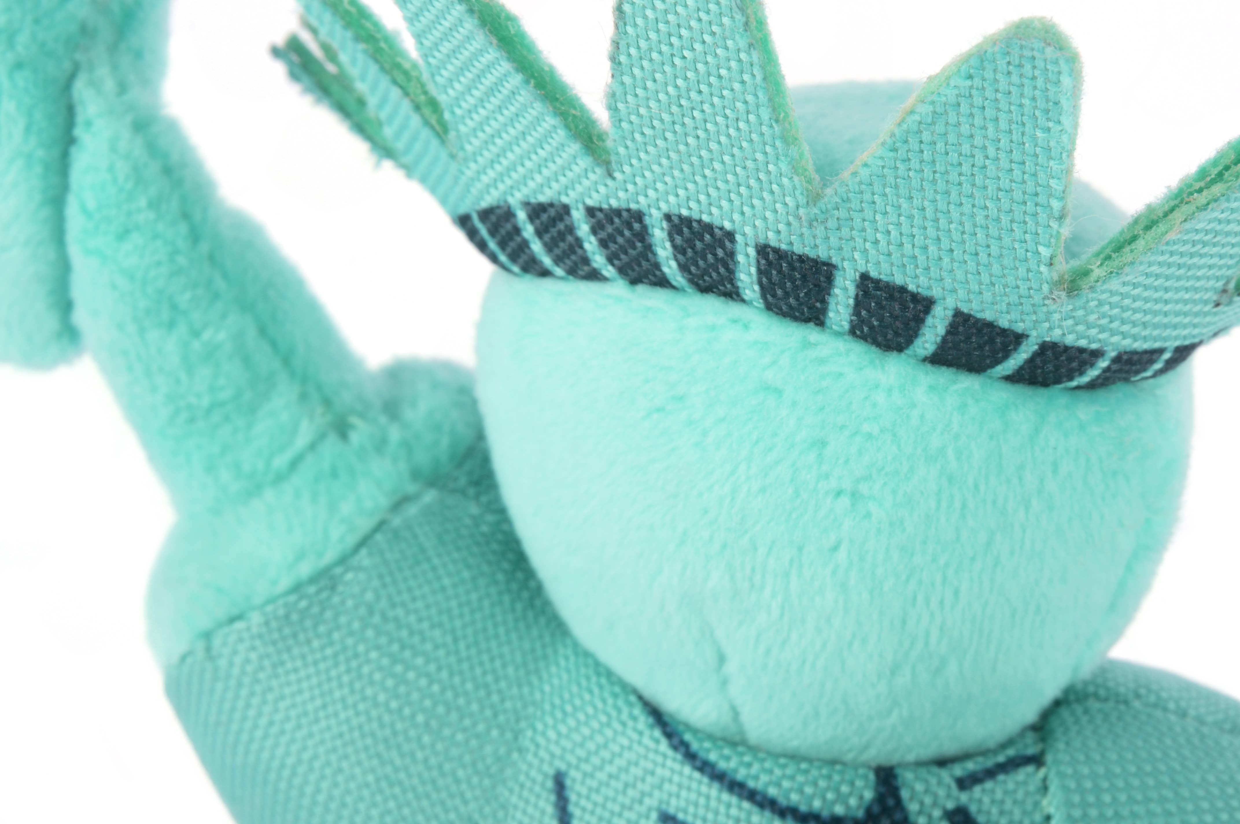 Close-up of a teal plush toy with black accents on a white background