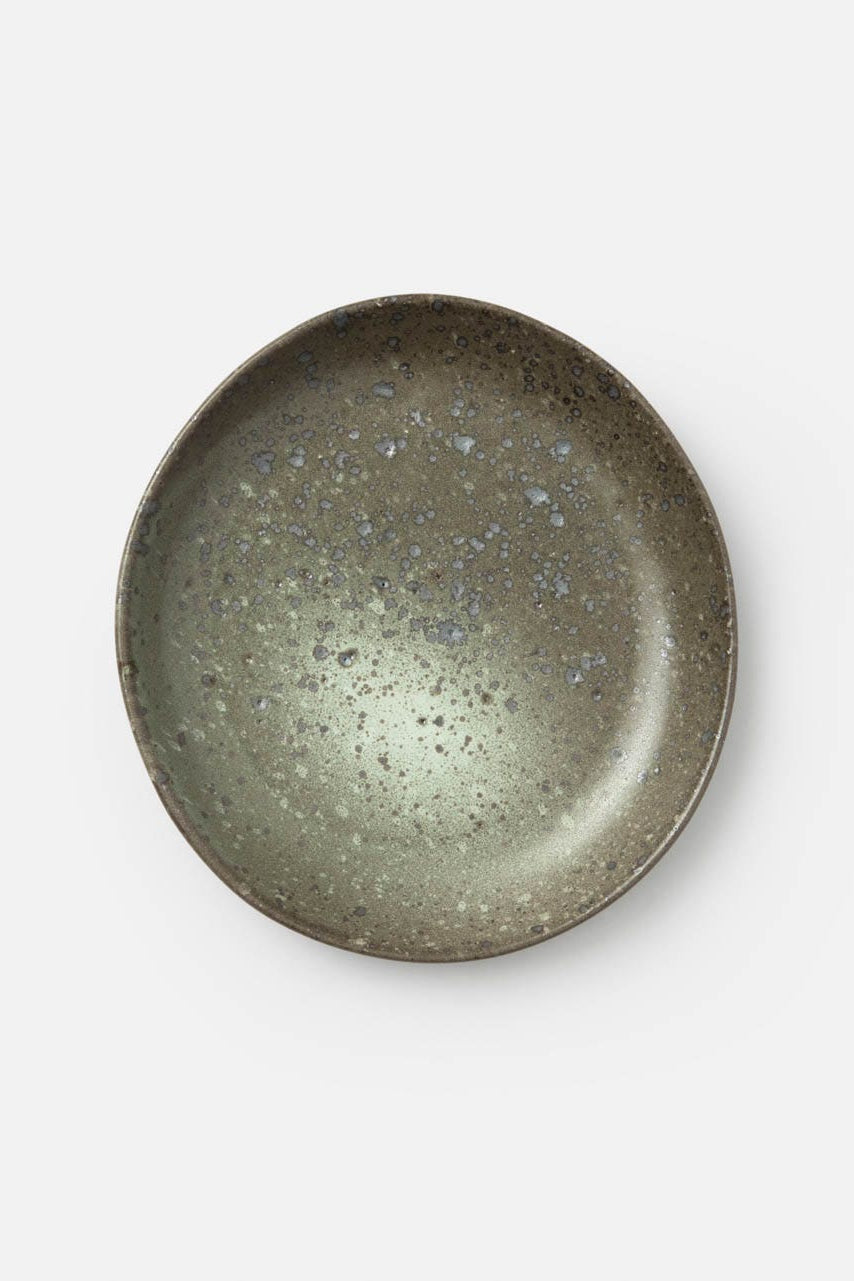 A round ceramic plate with a speckled, textured matte finish in earthy gray-green tones, photographed from directly above on a clean white background.
