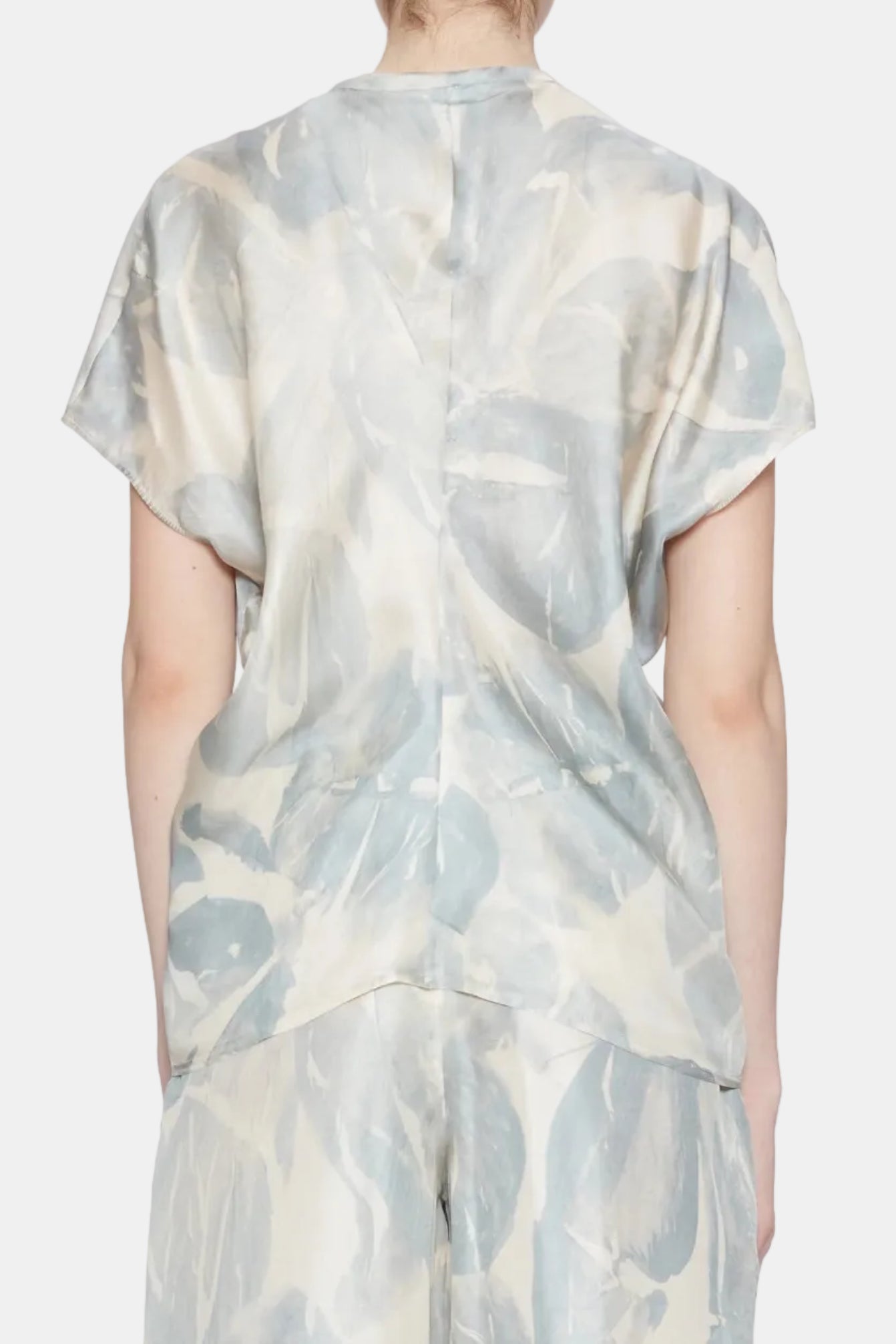 Person wearing a light-colored outfit with abstract pattern on a white background