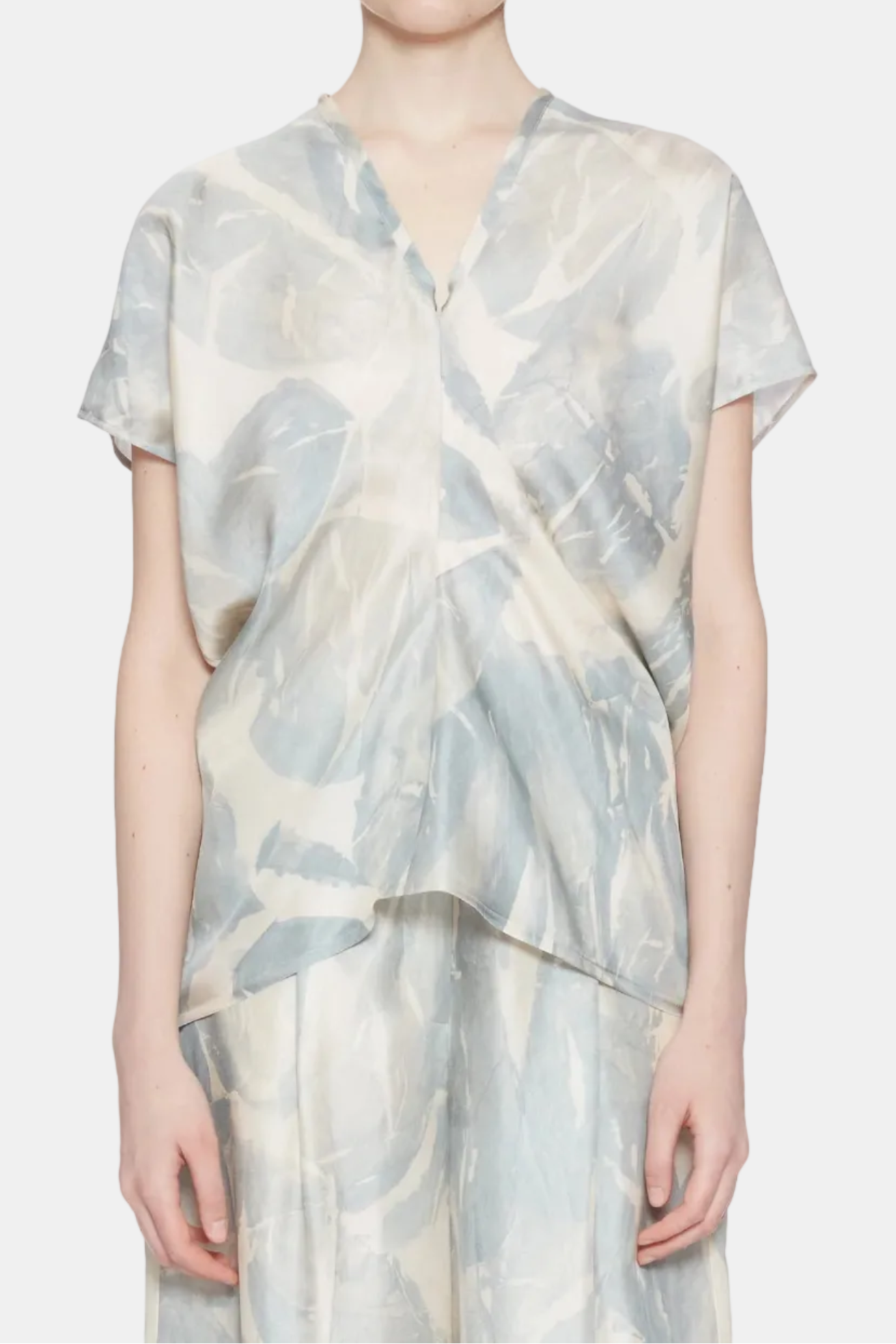 A model wearing a light blue and cream abstract patterned short-sleeve top and matching trousers against a plain white background.