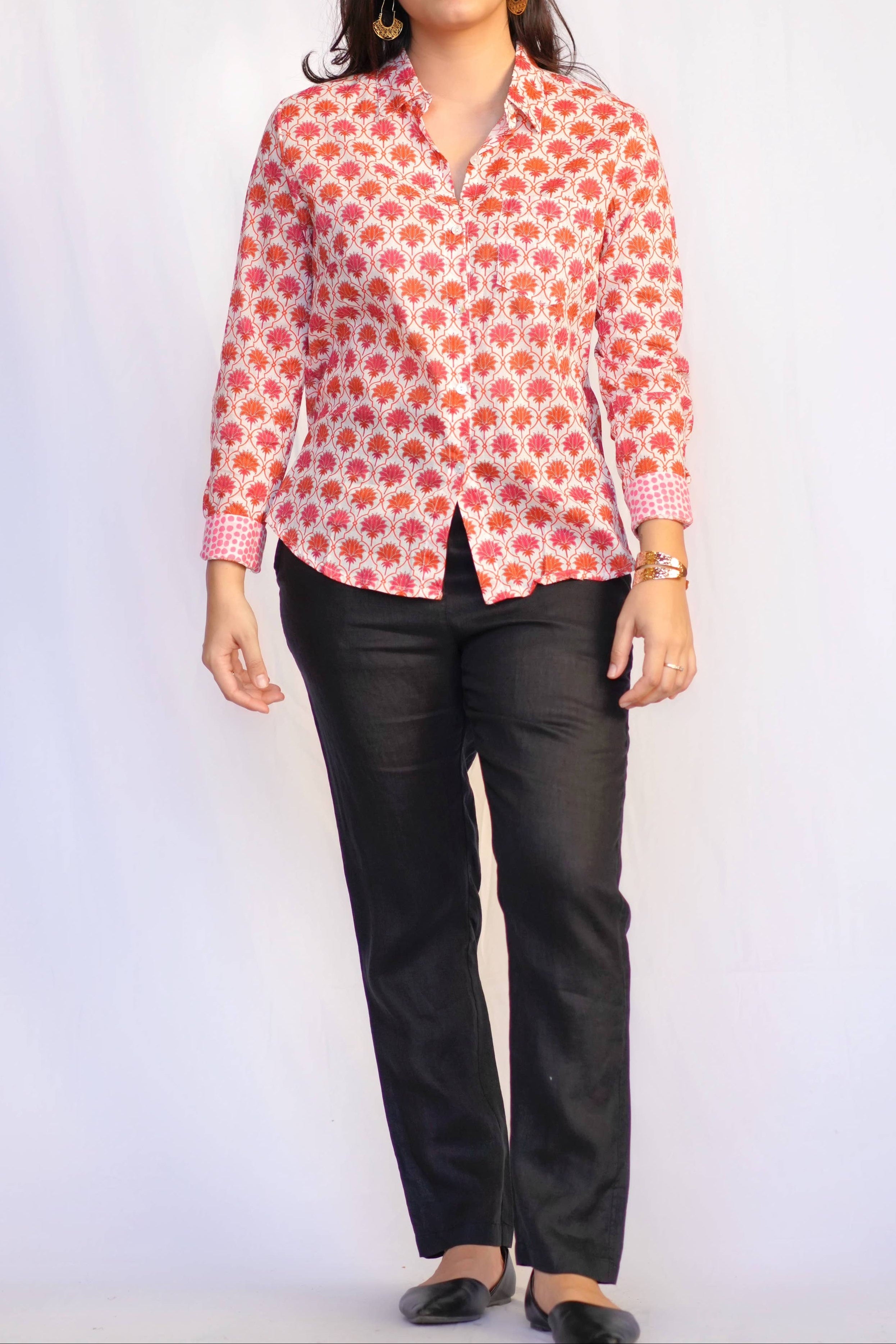 Woman wearing a red floral blouse and black pants on a white background