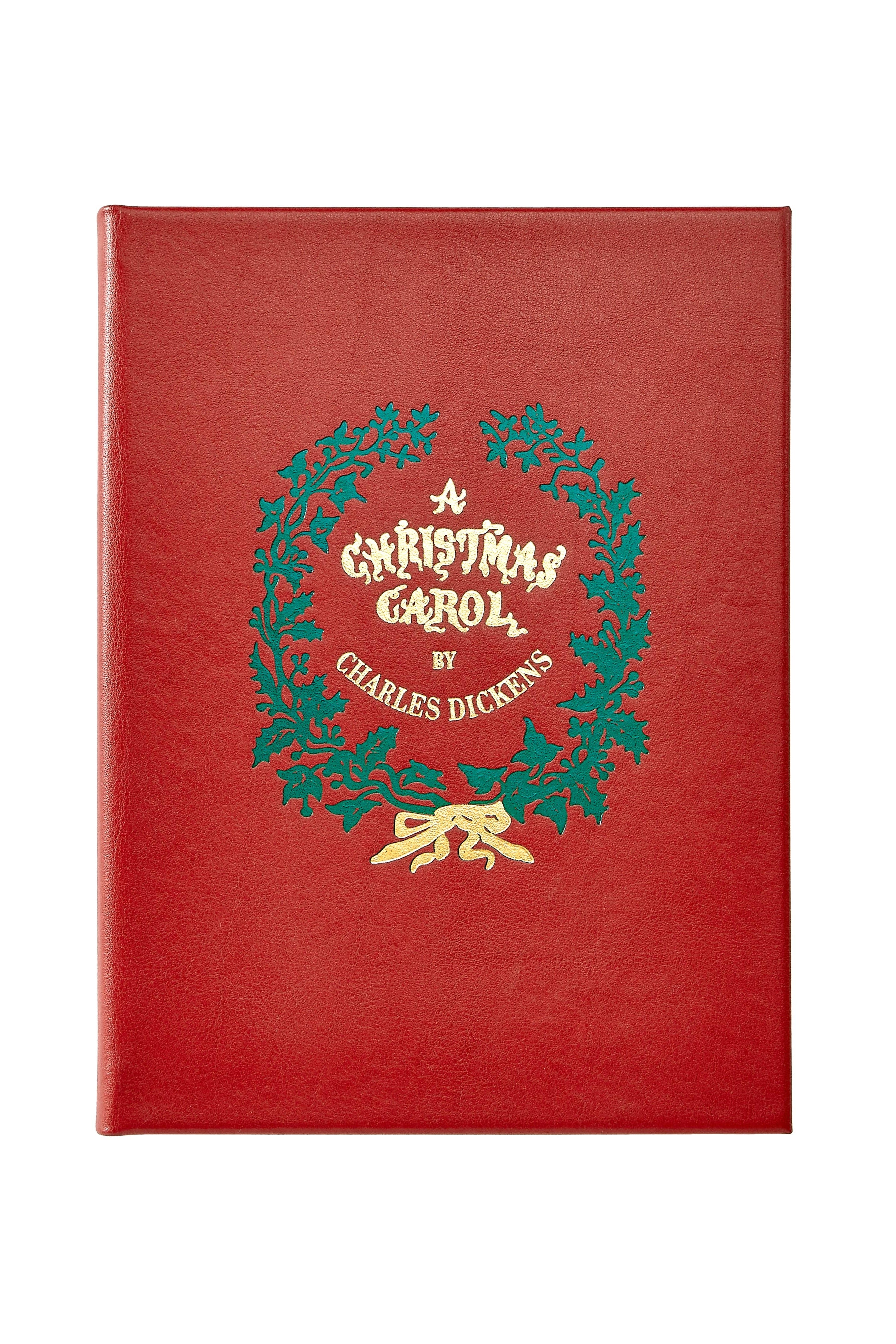 Red book cover with green wreath and gold text 'A Christmas Carol by Charles Dickens' on a white background