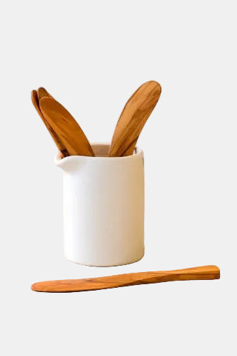 White ceramic container with wooden utensils on a wooden surface