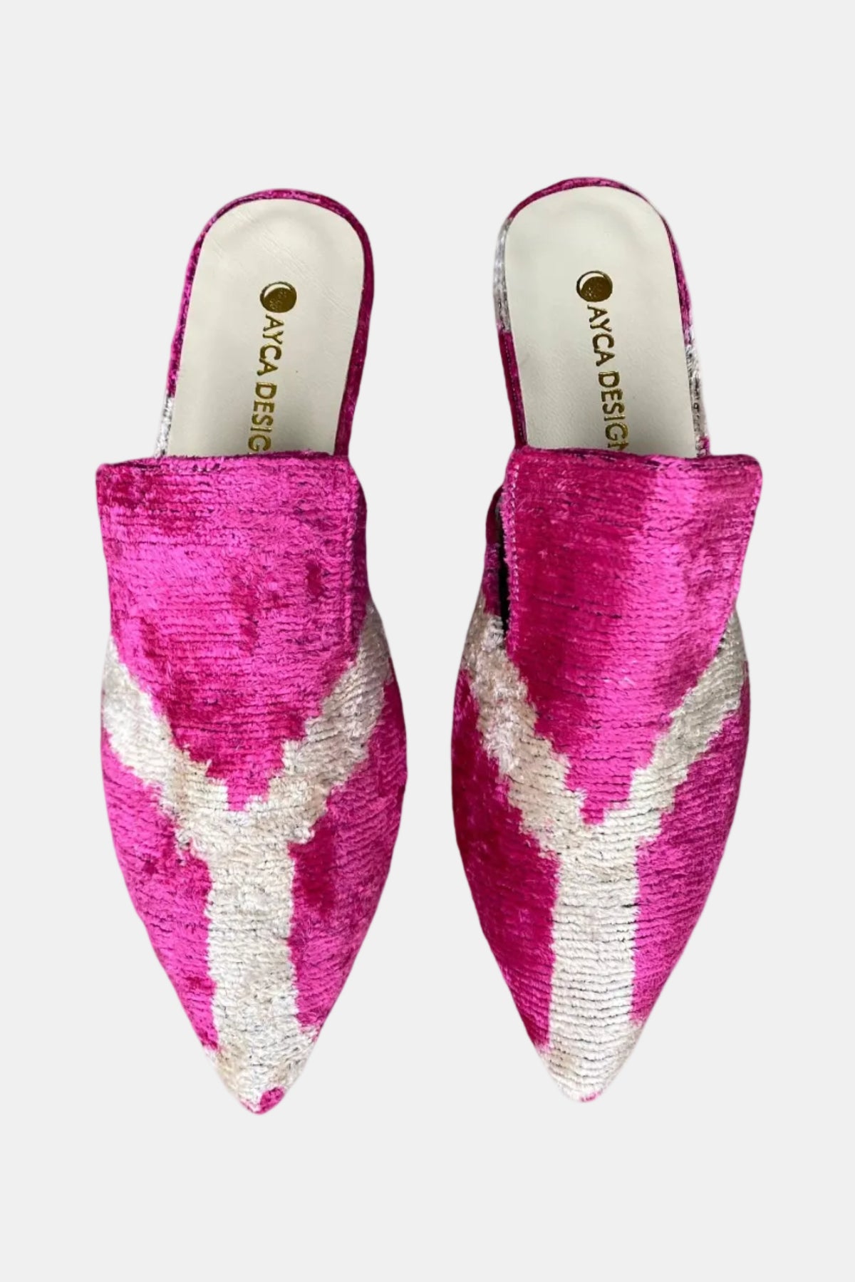 A pair of pointed-toe mule slippers in textured pink and white fabric, featuring a chevron pattern and the brand name 'AYDA DESIGNS' printed on the insole.