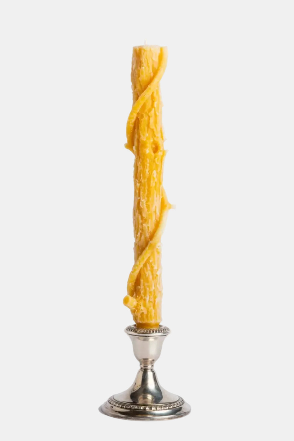 Tall, twisted yellow candle on a silver candlestick against a white background