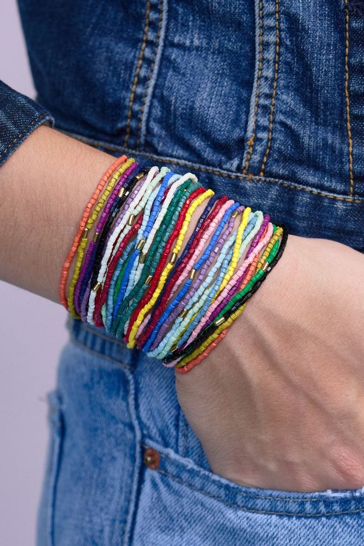 Multicolored bracelets on a wrist with a denim background