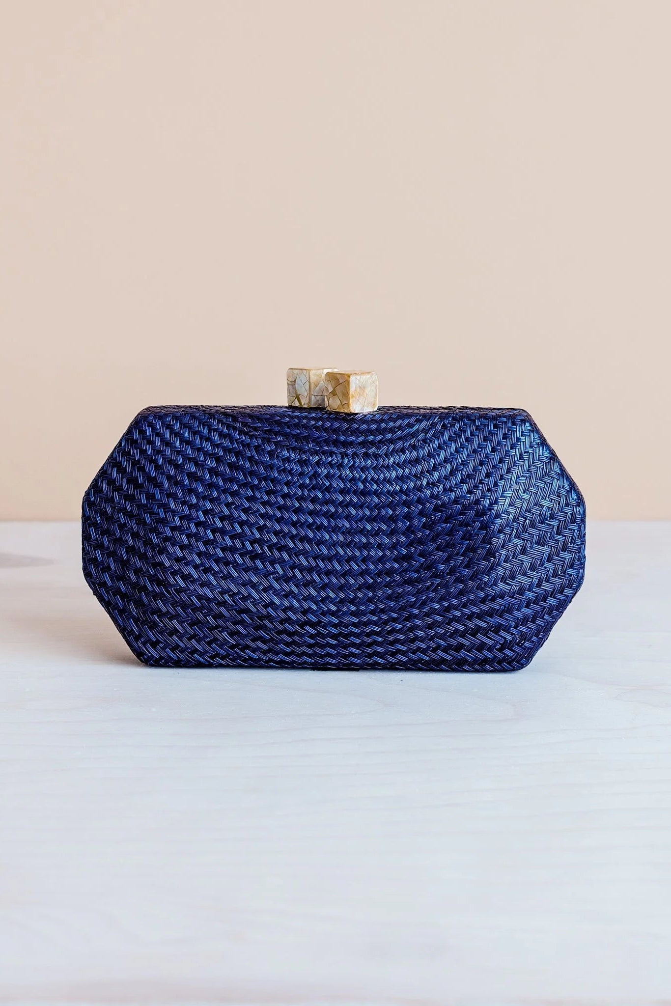 Blue woven clutch bag on a light surface with a beige background