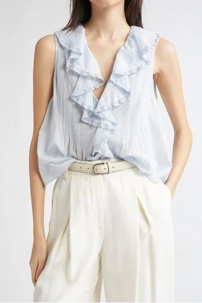 A model wearing a light blue ruffled sleeveless blouse tucked into cream wide-leg trousers with a beige belt, photographed against a light gray studio background.