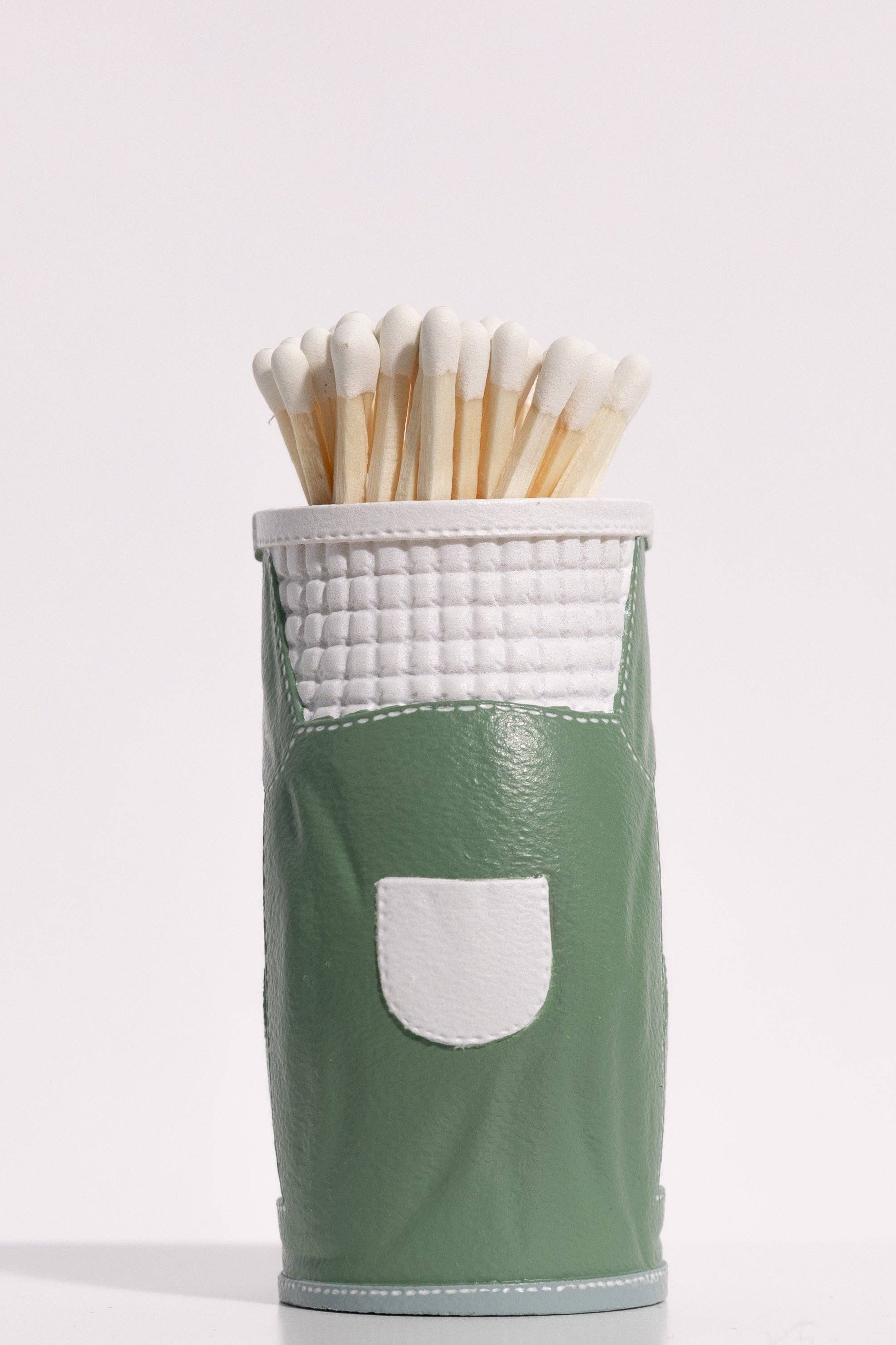Green matches holder with white wick matches on a light gray background