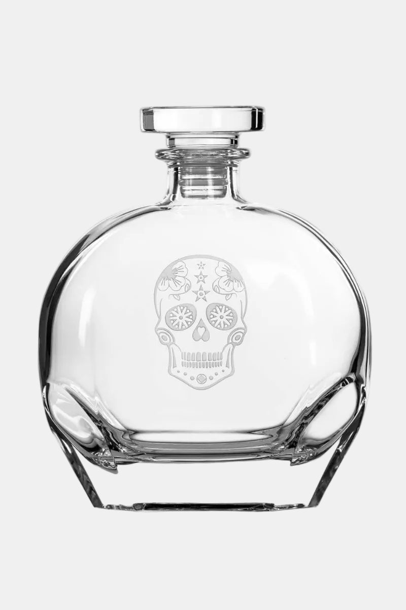 Clear glass decanter with skull design on a white background