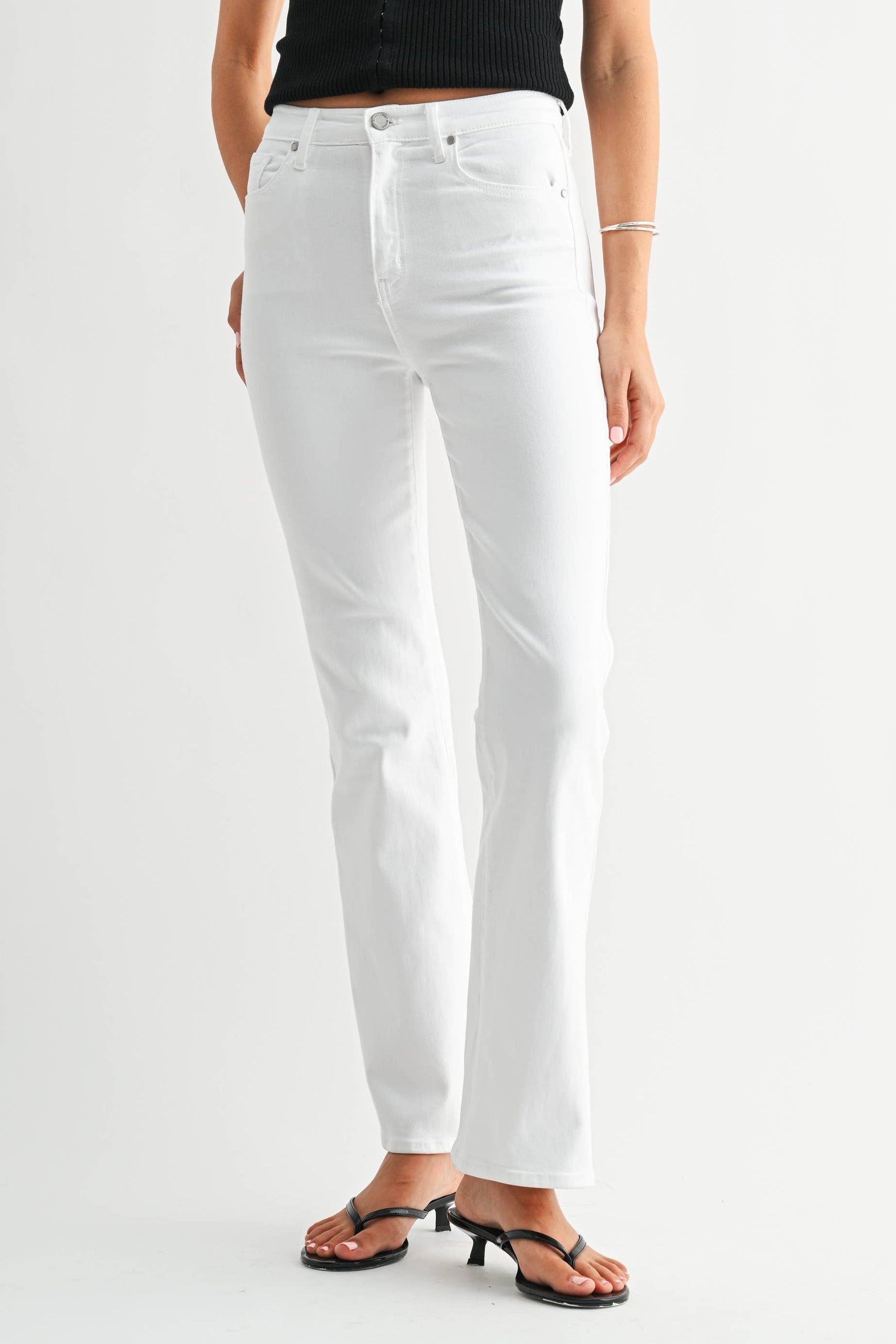 Woman wearing a black tank top and white jeans on a white background