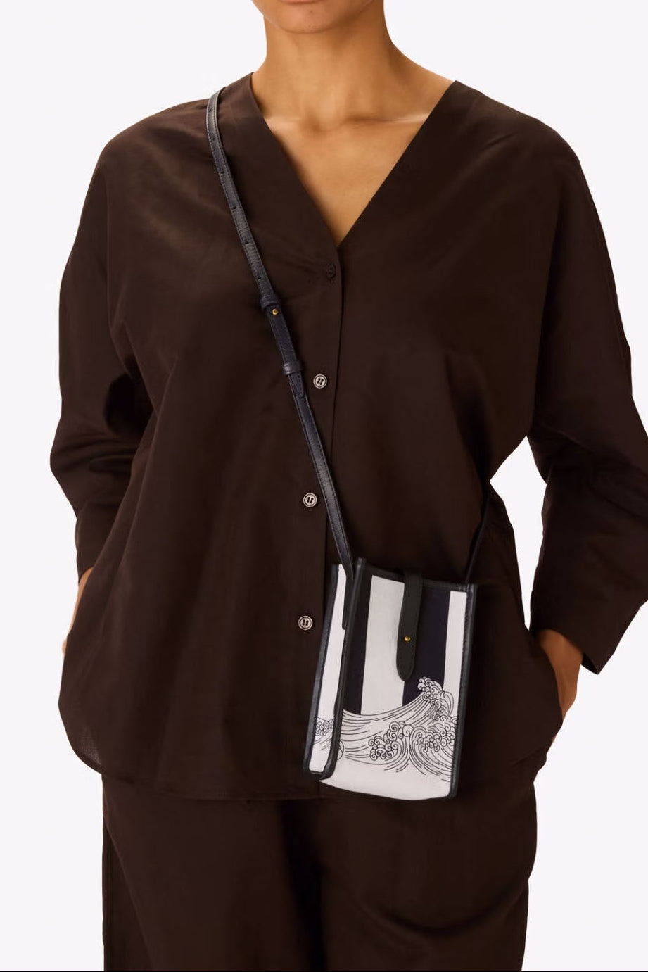 Woman wearing a brown outfit with a black and white handbag on a white background